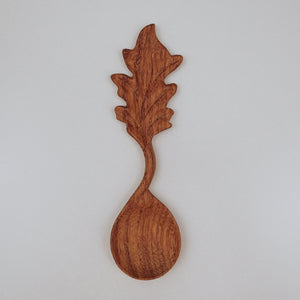 A handcrafted wooden spoon featuring a carved leaf cutout on the handle, ideal for bringing a forest-inspired feel to children’s outdoor play.