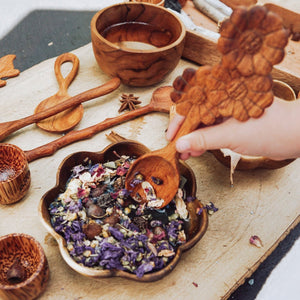 A larger wooden bowl carved in the shape of a flower, ideal for mixing potions or gathering natural treasures during outdoor play. Tuckered Out.